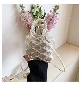 Detail of woven pearl bucket bag with canvas drawstring pouch and crossbody strap