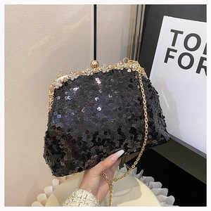 Detail of a black sequined evening bag with a gold floral crystal clasp and chain strap