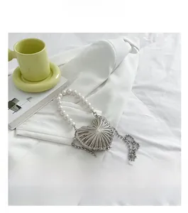 Close-up of heart-shaped silver metal mini bag with pearl handle on white blazer
