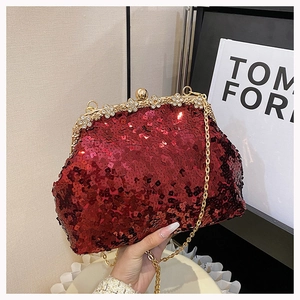 Detail of red sequined evening clutch with gold floral crystal clasp and chain strap