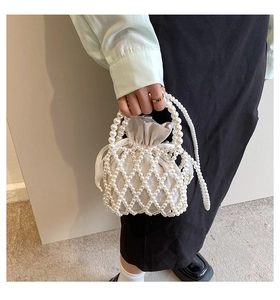 Detail of hand-woven pearl bucket bag with cream drawstring liner and pearl strap