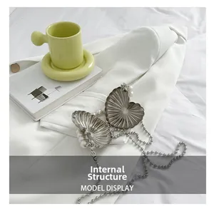 Detailed interior view of shell-shaped silver metal mini bag with pearl trim and chain