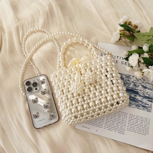 Elegant white pearl woven handbag with top handle and crossbody strap on stylish background