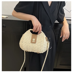 Dettaglio borsa in paglia intrecciata crema con patta in pelle marrone e chiusura oro