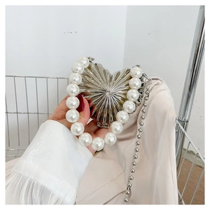 Detail of silver heart-shaped evening bag with pearl handle and metallic pleated texture