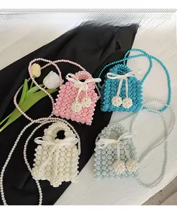 Detail of handcrafted mini pearl crossbody bags with satin bows and long pearl straps