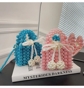 Close-up of handmade pearl beaded handbags with silk drawstring lining in blue and pink