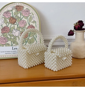Detail of two-piece cream white pearl woven handbags set on a rustic wooden table
