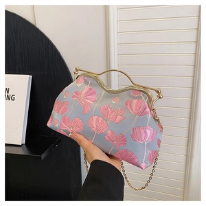 Detail of light blue satin evening bag with floral embroidery and gold metal handle