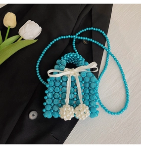 Detail of blue beaded handbag featuring a white satin bow and decorative pearls