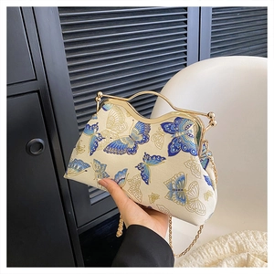 Macro shot of vintage chain bag featuring blue butterfly embroidery and gold metal handle