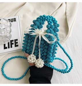 Detail of blue pearl woven handbag featuring a white satin bow and a pearl crossbody strap