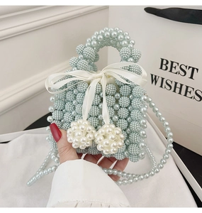 Close-up of a light blue pearl woven handbag with a white satin bow and pearls