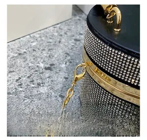 Detail of gold hardware hook and silver rhinestones on luxury black cylinder evening bag