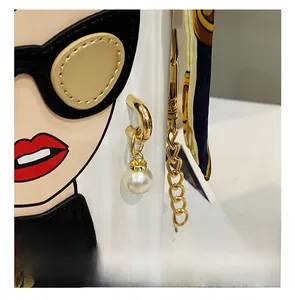 Macro shot of fashion box bag featuring pearl charm, gold chain, and printed silk scarf