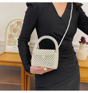 Detail of white handmade pearl woven handbag showing pearl handle and crossbody strap