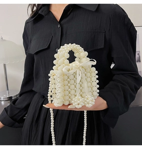 Detail of hand-woven white pearl handbag with a silky ribbon bow and pearl handle