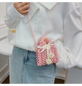 Pink handmade pearl woven mini bag featuring white silk bow and matching strap