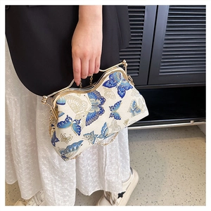 Detail of vintage cream handbag with blue butterfly embroidery and gold chain strap