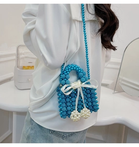 Detail of navy beaded handbag with a white velvet bow and pearl charms for women