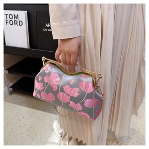 Detail of pink floral embroidery and golden metal handle on a grey vintage evening bag