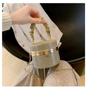 Close-up of sparkling rhinestone cylinder evening bag with pleated green handle and chain