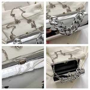 Macro details of silver cylindrical clutch bag with thick metallic chain and mirror finish