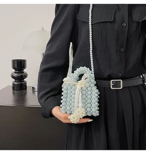 Detail of light blue pearl woven bag with white satin bow and elegant pearl strap