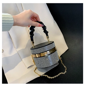 Macro shot of rhinestone cylinder evening bag with pleated black handle and gold chain