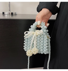 Detail of light blue pearl woven handbag with silk bow and large pearl pendants