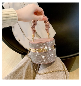 Macro view of crystal cylinder evening bag with pink pleated handle and gold chain strap