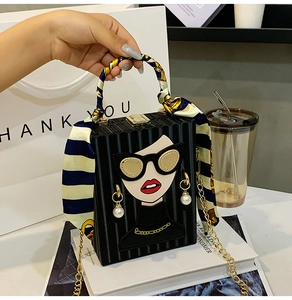 Detailed view of black box bag with fashion girl character and silk scarf handle