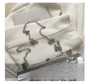 Detail of silver metallic cylinder bag with chunky chain handle on a minimal background