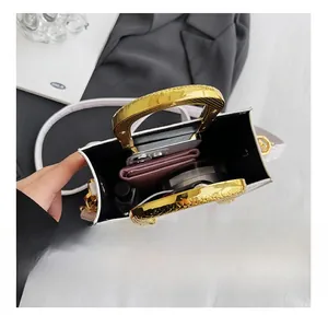 Internal capacity of white embossed handbag with gold handles showing phone and makeup