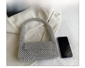 Silver beaded rhinestone bag on beige blazer with phone for scale comparison