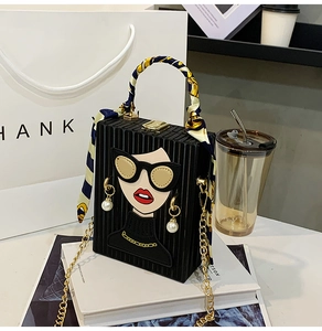 Detail of black box bag with fashion face motif and silk scarf wrapped handle
