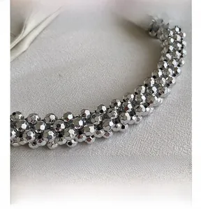 Macro view of metallic faceted beads and woven texture on silver handbag handle
