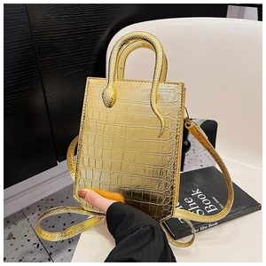 Detail of golden crocodile embossed handbag featuring a unique metallic snake handle