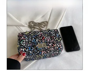 Detail view of graffiti tweed crossbody bag showing size compared to a smartphone