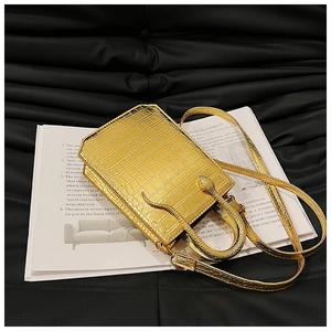 Macro shot of glossy gold crocodile pattern handbag featuring a unique snake-shaped handle