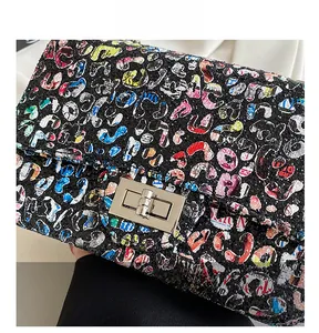 Detailed close-up of a silver metal swivel lock on a colorful graffiti flap bag