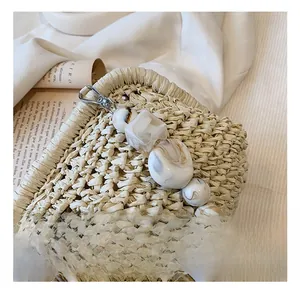 Close-up of woven straw bag featuring marble texture acrylic beads and silver metal hook