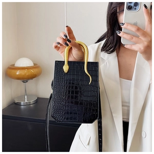Detail of glossy black crocodile texture bag with golden snake-shaped metal handle