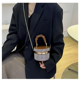 Detail of rhinestone cylindrical evening bag with pleated brown handle and gold chain