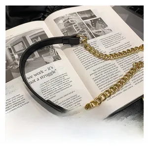 Detailed shot of golden metal chain strap with black leather shoulder pad on magazine