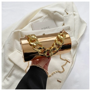 Detail of rose gold cylindrical clutch featuring a chunky gold chain and metallic finish