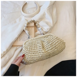 Detail of woven straw bag with marbled resin bead handle on white blazer background