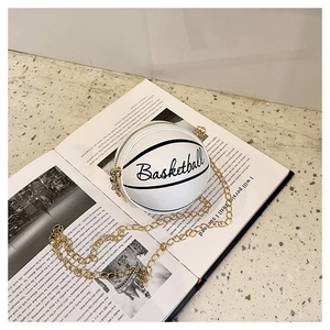 Detail of creative white basketball shaped mini crossbody bag with gold chain on a book