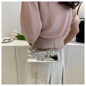 Detail view of a silver cylindrical shoulder bag with chunky chain and metallic finish