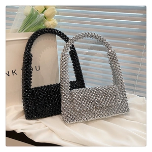Detail view of woven beaded handbags in glossy black and silver on white satin fabric